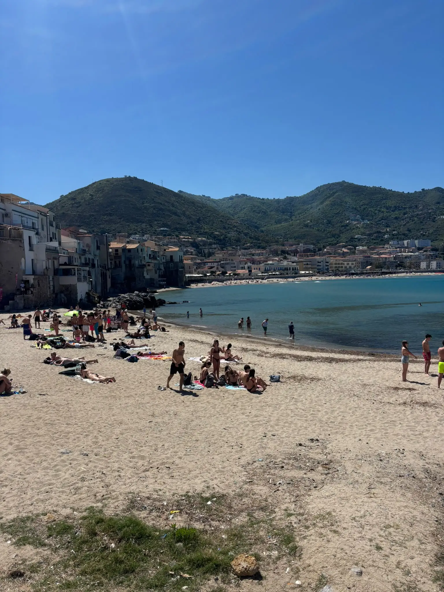 Playa de Cefalú, en Sicilia, con las casas del pueblo y las montañas verdes detrás